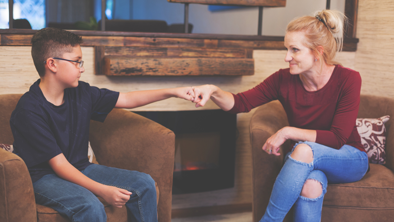 Therapist and young boy bumping fists during session